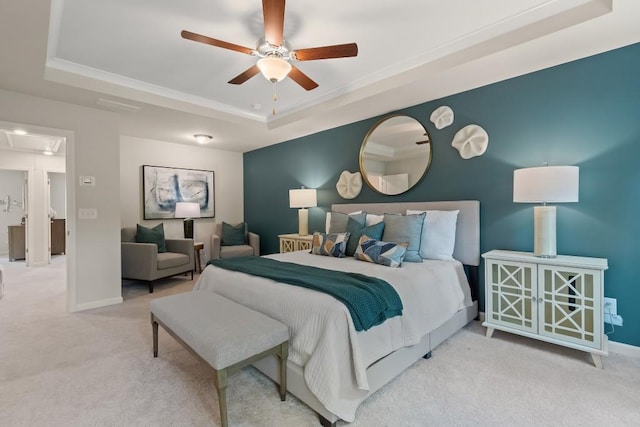 carpeted bedroom featuring a tray ceiling, attic access, baseboards, and ceiling fan