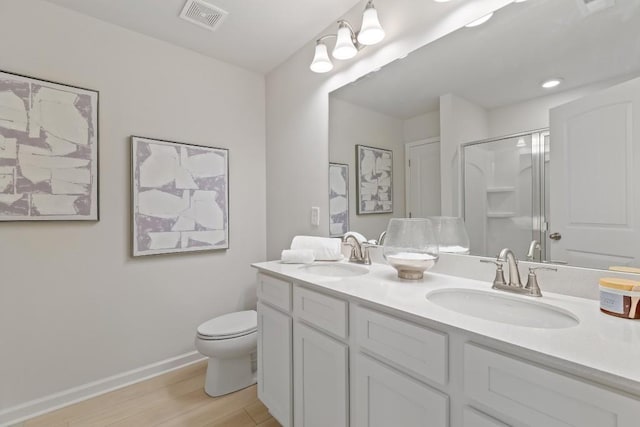 bathroom with wood finished floors, baseboards, an enclosed shower, double vanity, and toilet