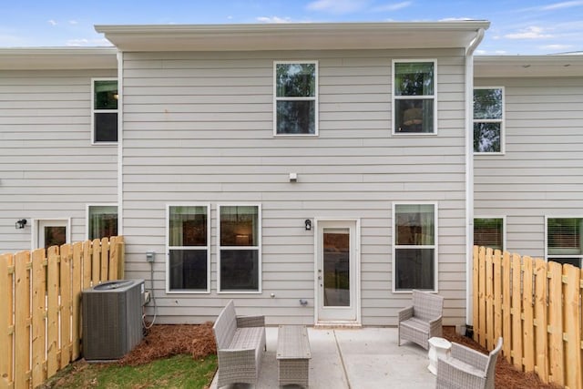 rear view of property with central air condition unit, a fenced backyard, and a patio