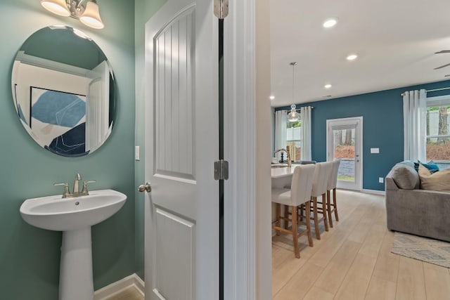 bathroom featuring wood finished floors, recessed lighting, a sink, and baseboards