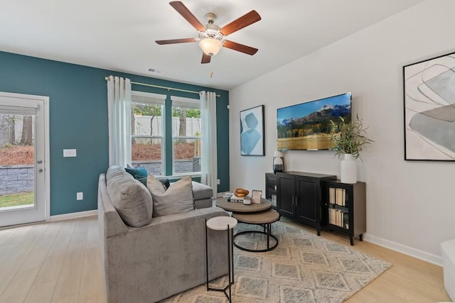 living area featuring light wood-style flooring, a ceiling fan, and baseboards