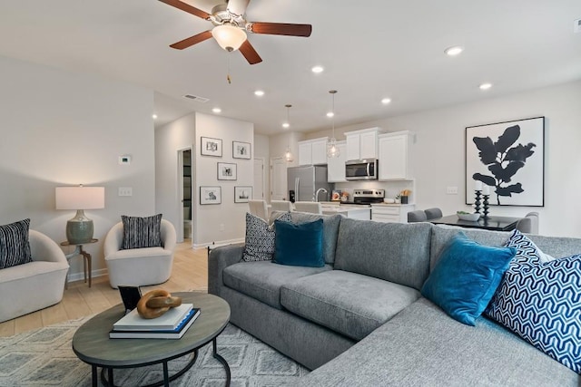 living room with light wood-style floors, ceiling fan, baseboards, and recessed lighting