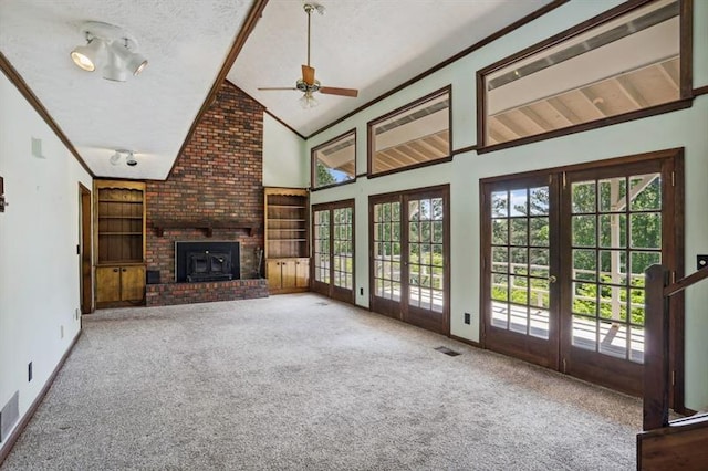 unfurnished living room with ceiling fan, carpet flooring, a wood stove, a textured ceiling, and french doors