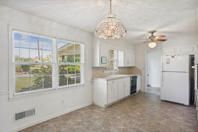 kitchen featuring white fridge, ceiling fan, hanging light fixtures, white cabinets, and sink