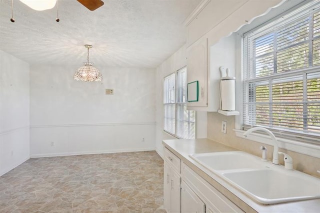 kitchen featuring a textured ceiling, white cabinets, decorative light fixtures, sink, and ceiling fan