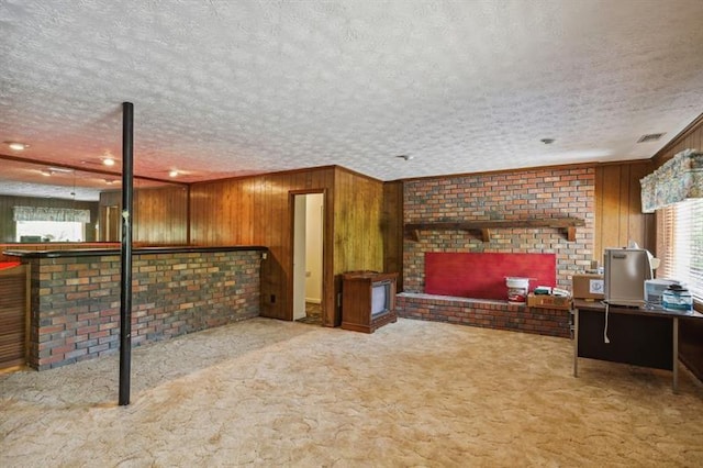 carpeted living room featuring wooden walls and a textured ceiling