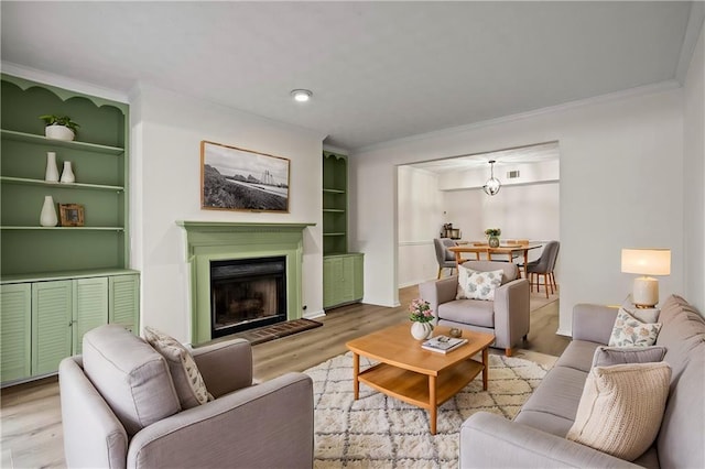 living room featuring crown molding, light wood-type flooring, and built in shelves