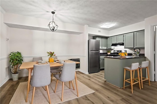 kitchen with appliances with stainless steel finishes, a notable chandelier, a textured ceiling, dark hardwood / wood-style flooring, and decorative light fixtures