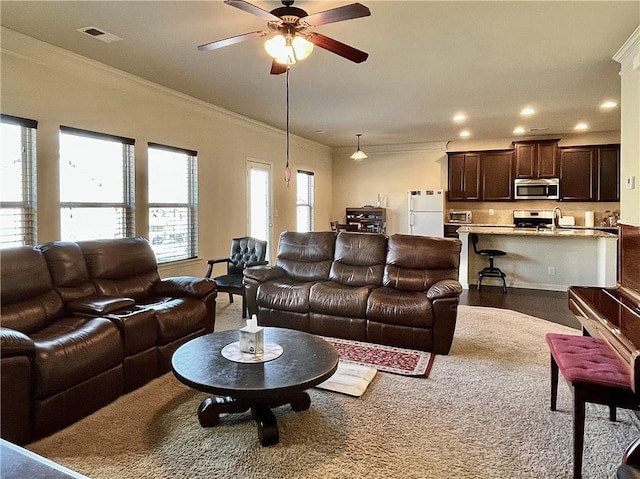 living room featuring a ceiling fan, recessed lighting, visible vents, and crown molding