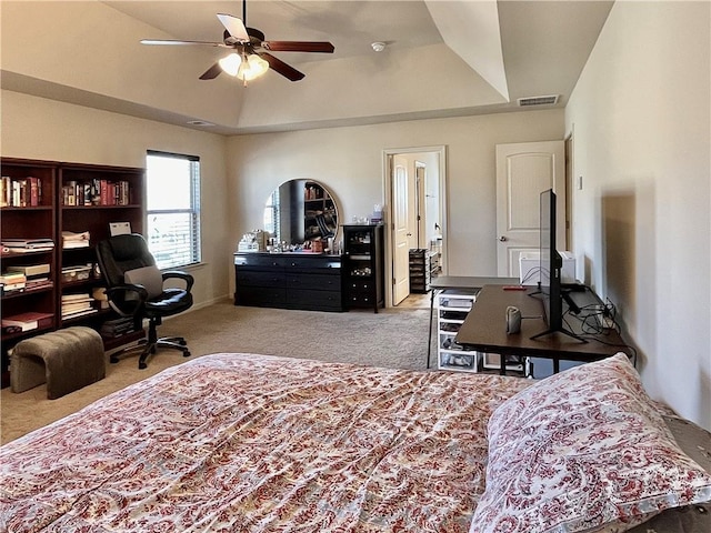 carpeted bedroom featuring ceiling fan, a raised ceiling, and visible vents