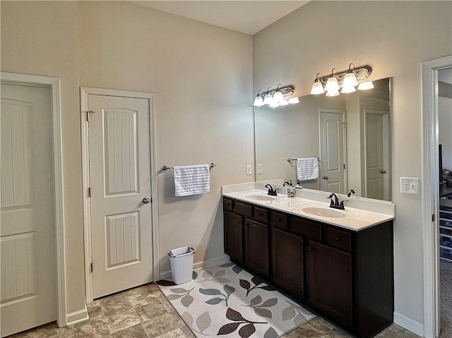 bathroom featuring a sink, baseboards, and double vanity