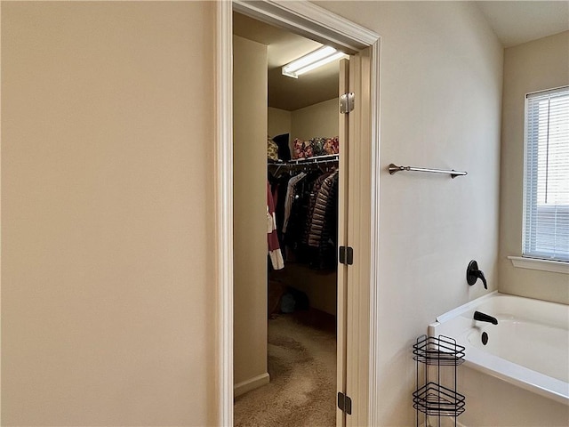 bathroom featuring a spacious closet and a garden tub