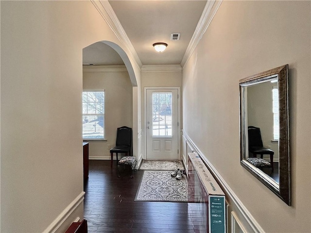 entryway featuring arched walkways, dark wood-type flooring, visible vents, baseboards, and crown molding