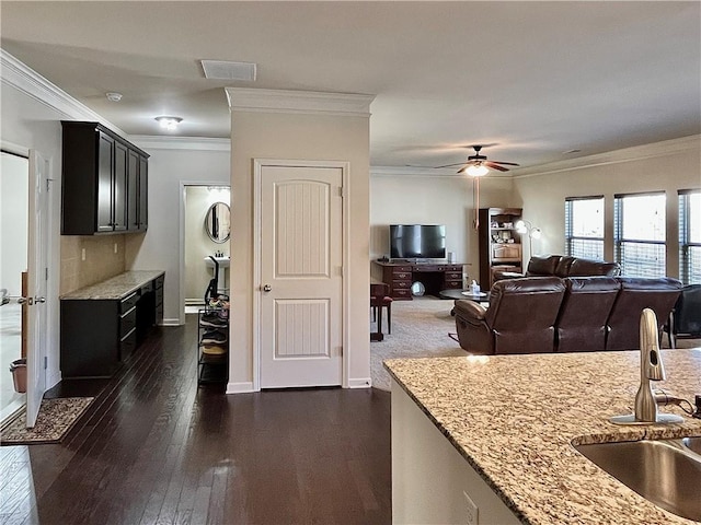 kitchen featuring crown molding, a sink, and light stone counters