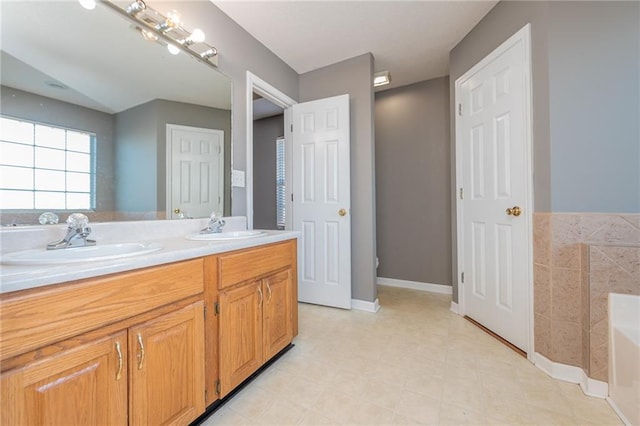 bathroom with double vanity, a washtub, baseboards, and a sink