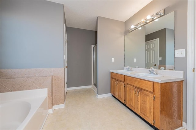 bathroom featuring double vanity, a stall shower, a garden tub, and a sink