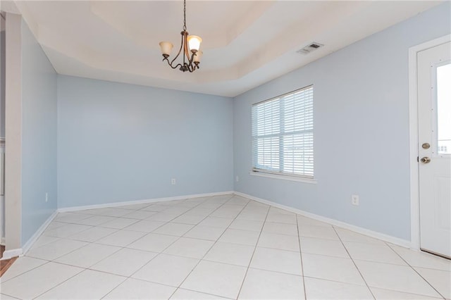 spare room with visible vents, a notable chandelier, a tray ceiling, light tile patterned floors, and baseboards