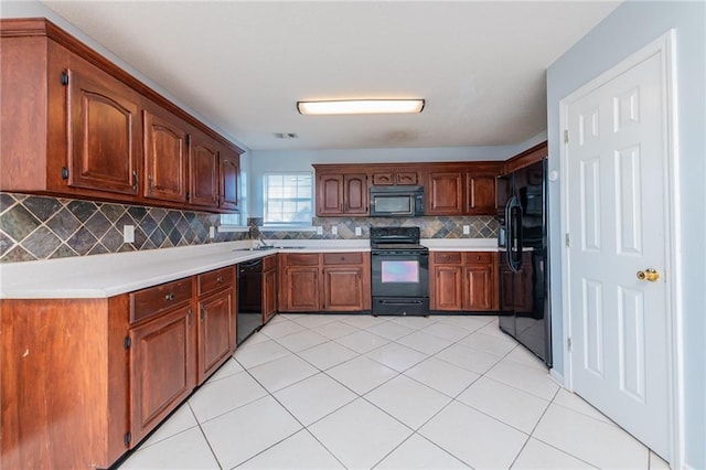 kitchen with light tile patterned floors, decorative backsplash, black appliances, and light countertops