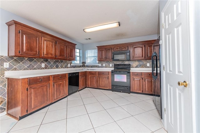 kitchen featuring visible vents, light countertops, decorative backsplash, black appliances, and a sink