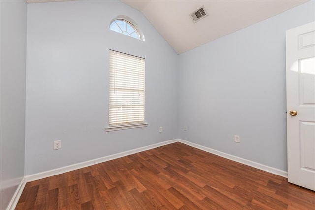 spare room featuring visible vents, baseboards, dark wood-style floors, and vaulted ceiling