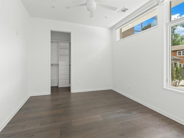 unfurnished bedroom featuring a closet, dark hardwood / wood-style floors, multiple windows, and ceiling fan