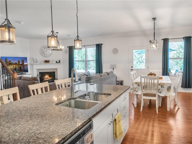 kitchen with sink, decorative light fixtures, dark stone counters, and white cabinets