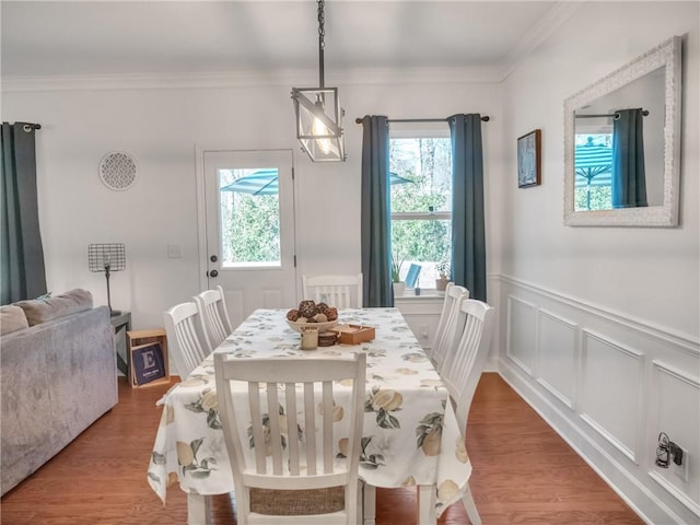 dining space with hardwood / wood-style flooring, crown molding, and a healthy amount of sunlight