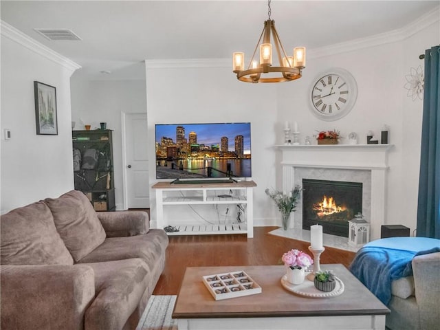 living room with hardwood / wood-style floors, a fireplace, ornamental molding, and a chandelier