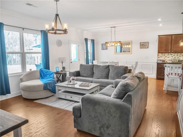 living room featuring an inviting chandelier, crown molding, and hardwood / wood-style flooring