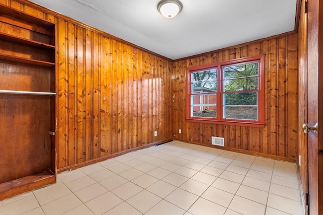 tiled empty room featuring wood walls