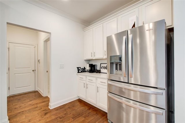 kitchen with ornamental molding, stainless steel refrigerator with ice dispenser, white cabinets, and dark hardwood / wood-style flooring