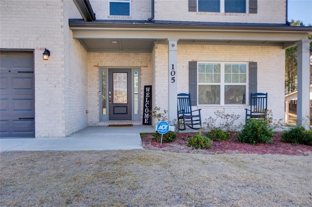 view of exterior entry featuring covered porch and a garage