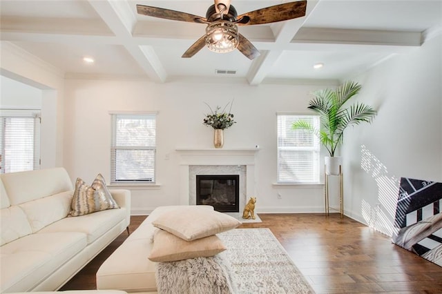 living room with coffered ceiling, a high end fireplace, beam ceiling, and a healthy amount of sunlight