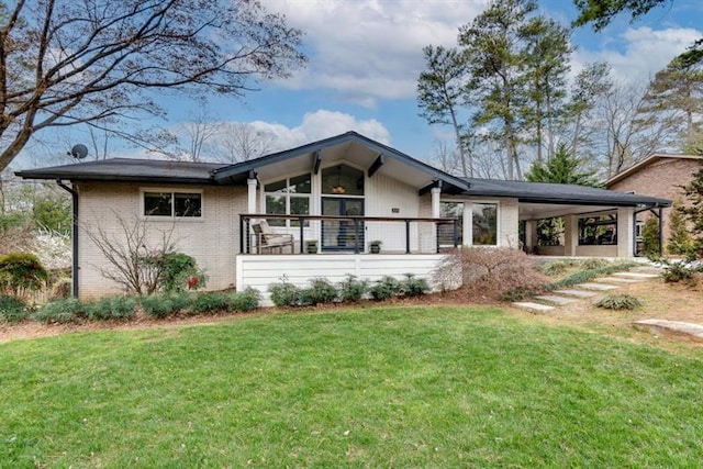 rear view of property with brick siding, an attached carport, and a yard