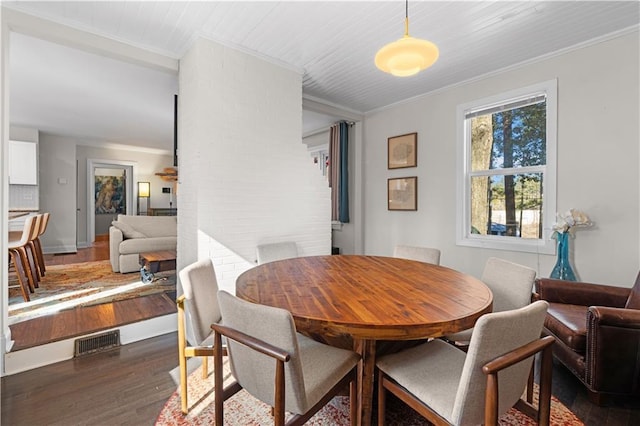 dining space with dark wood finished floors, visible vents, and crown molding