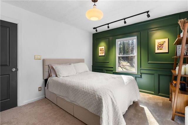 carpeted bedroom featuring rail lighting and a decorative wall