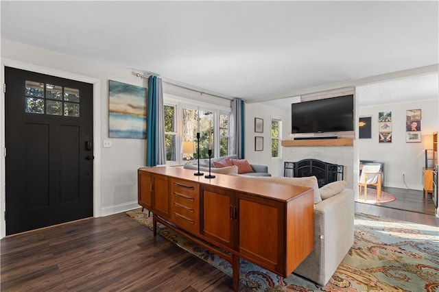 living area with a fireplace, dark wood finished floors, and baseboards