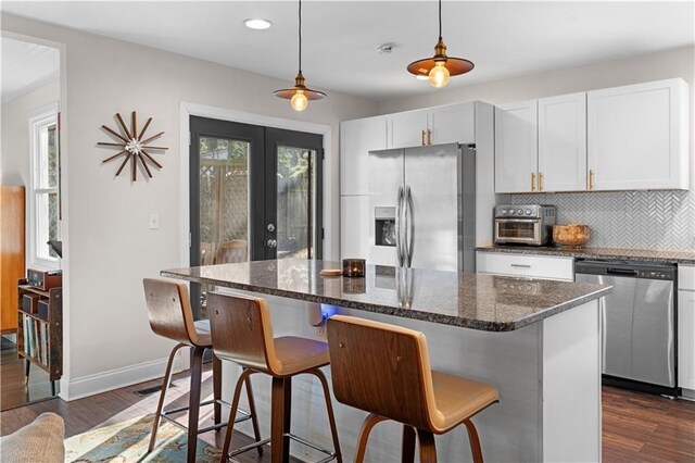 kitchen featuring white cabinets, decorative backsplash, dark wood-style flooring, stainless steel appliances, and french doors