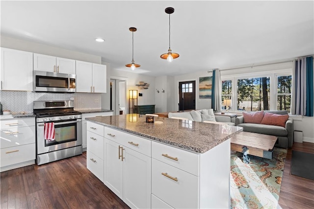 kitchen featuring dark wood-style floors, stainless steel appliances, backsplash, and a healthy amount of sunlight