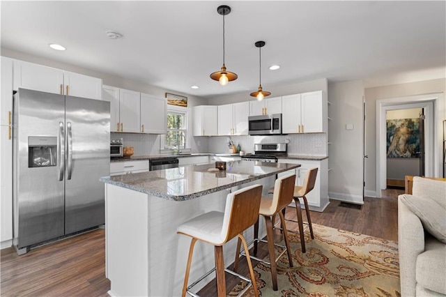 kitchen with stainless steel appliances, dark wood-type flooring, white cabinetry, and decorative backsplash