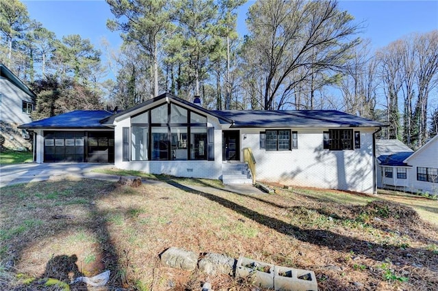 view of front facade with driveway, a sunroom, a garage, crawl space, and brick siding