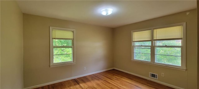 empty room with light wood-style floors, baseboards, and visible vents