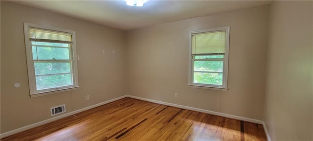 unfurnished room featuring baseboards, visible vents, and light wood-style floors