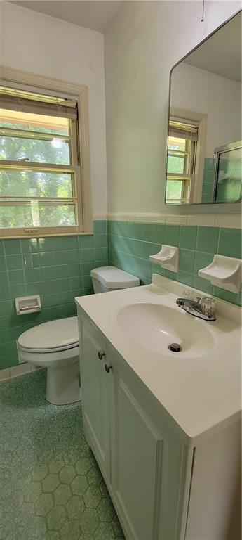 bathroom with toilet, tile walls, plenty of natural light, and tile patterned flooring