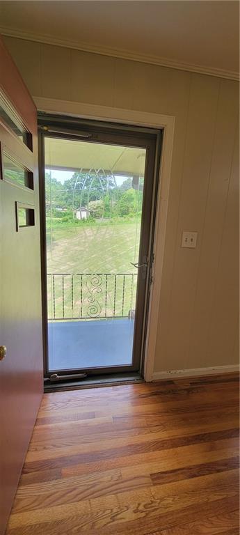 doorway with ornamental molding and wood finished floors