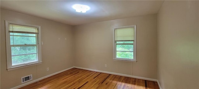 empty room featuring baseboards, visible vents, and light wood finished floors