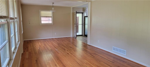 unfurnished room featuring baseboards, light wood finished floors, and visible vents
