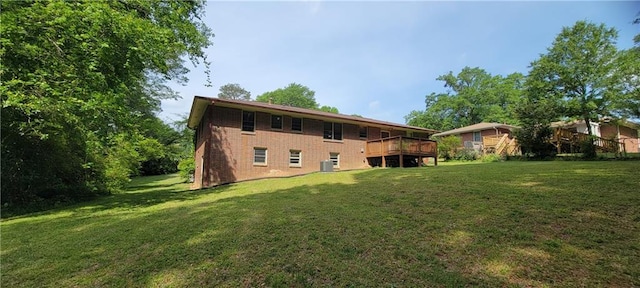 rear view of property featuring a yard, a deck, and brick siding