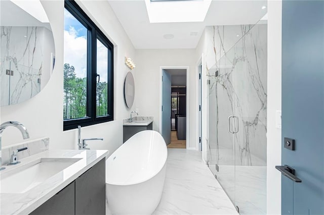 full bathroom with a freestanding tub, a sink, a marble finish shower, a skylight, and marble finish floor
