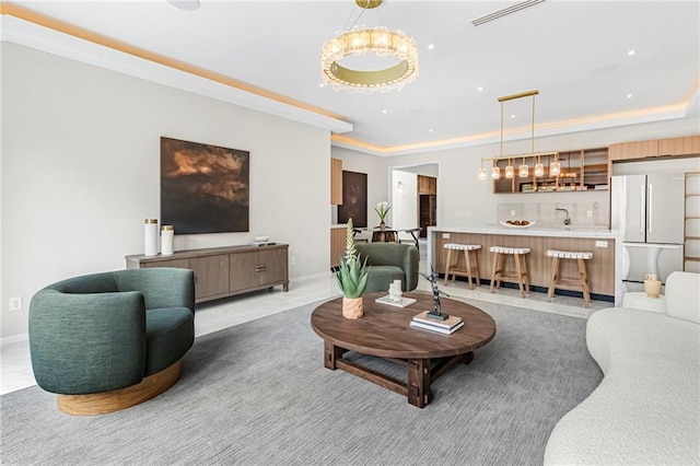living room with a tray ceiling, bar area, baseboards, and recessed lighting